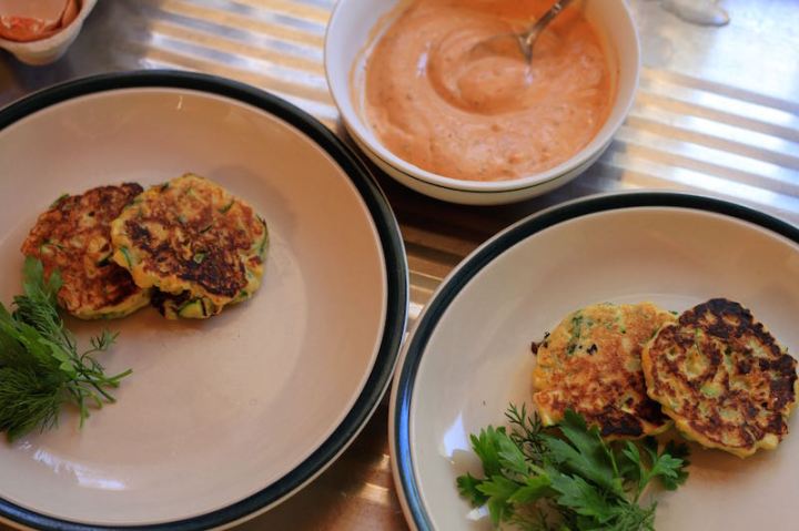 Plating up sweetcorn fritters and harrissa sauce