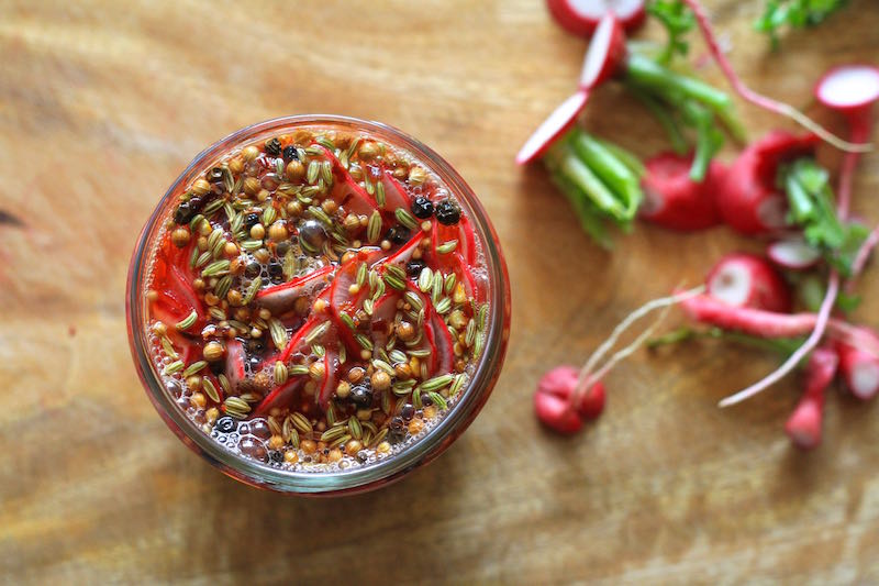 Sliced radishes topped with pickling brine - Quick Pickled Radishes