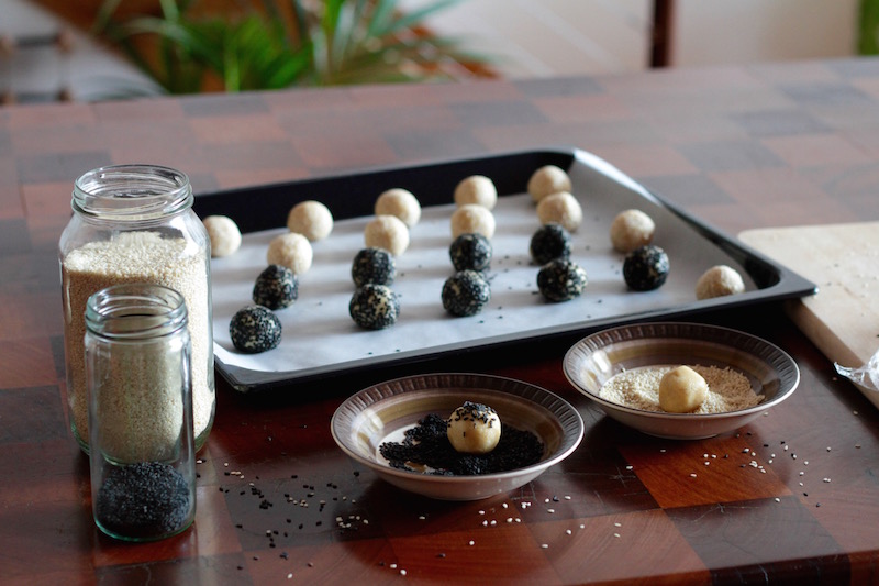 Preparing tahini cookies - rolling little balls of dough in sesame seeds