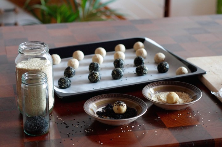 Preparing tahini cookies - rolling little balls of dough in sesame seeds